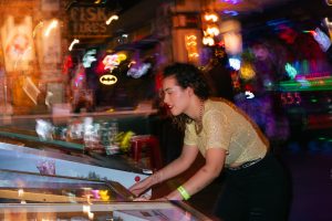 Young woman enjoying a night out playing pinball in an energetic arcade setting. — Accurate Football Predictions From This Se