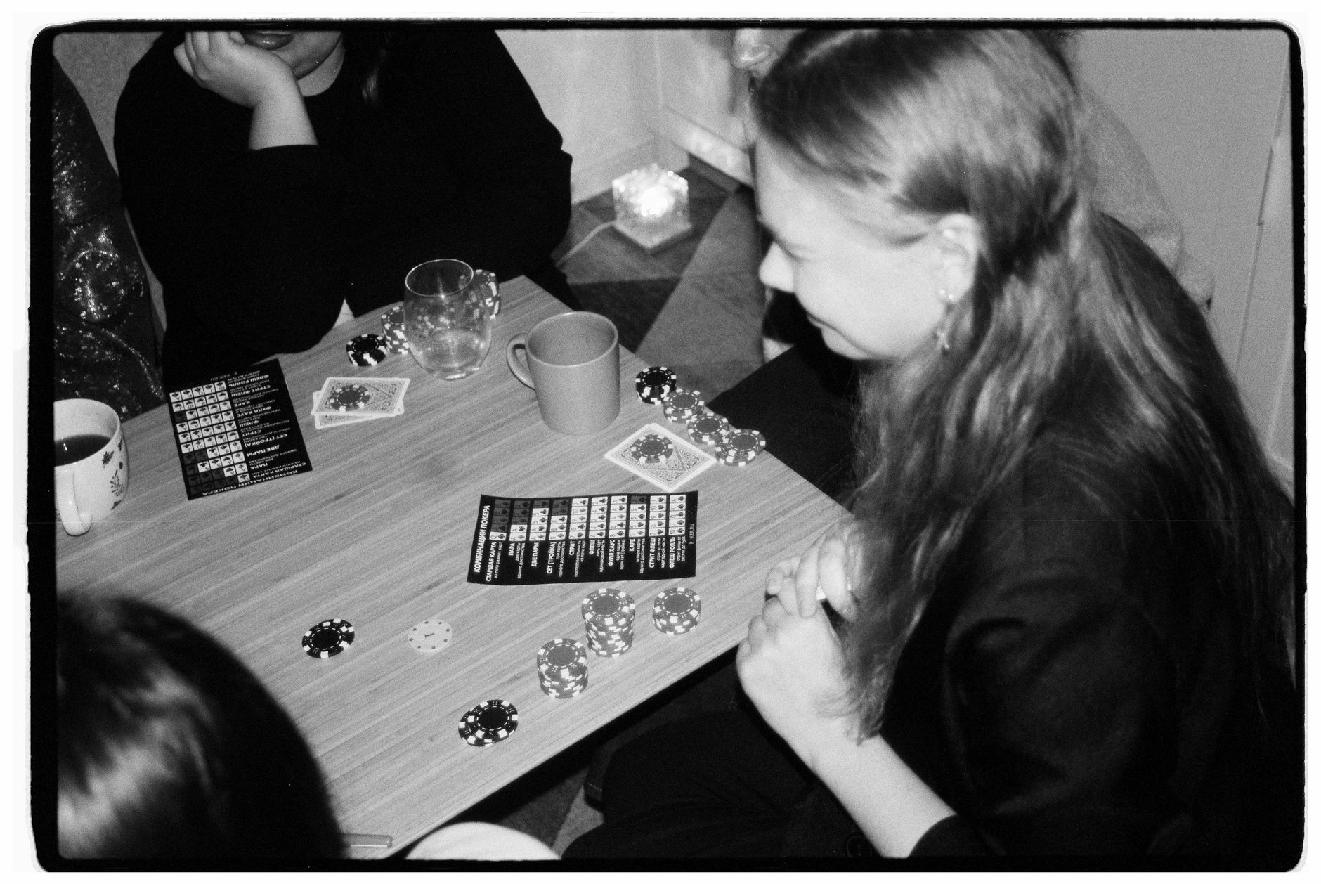 Group of friends enjoying a casual poker night indoors, captured in black and white. — DiscussingtheDisadvantagesofPlayingSlo