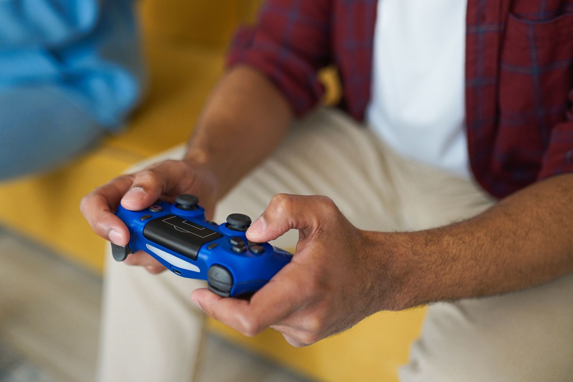 Hands holding a blue wireless game controller on a comfortable sofa indoors. — Evaluation of MPOID Alternative Link Availabil