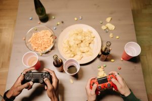 Two gamers playing video games with snacks and drinks on table, a perfect setup for gaming night. — How Casinos Build Long-Te