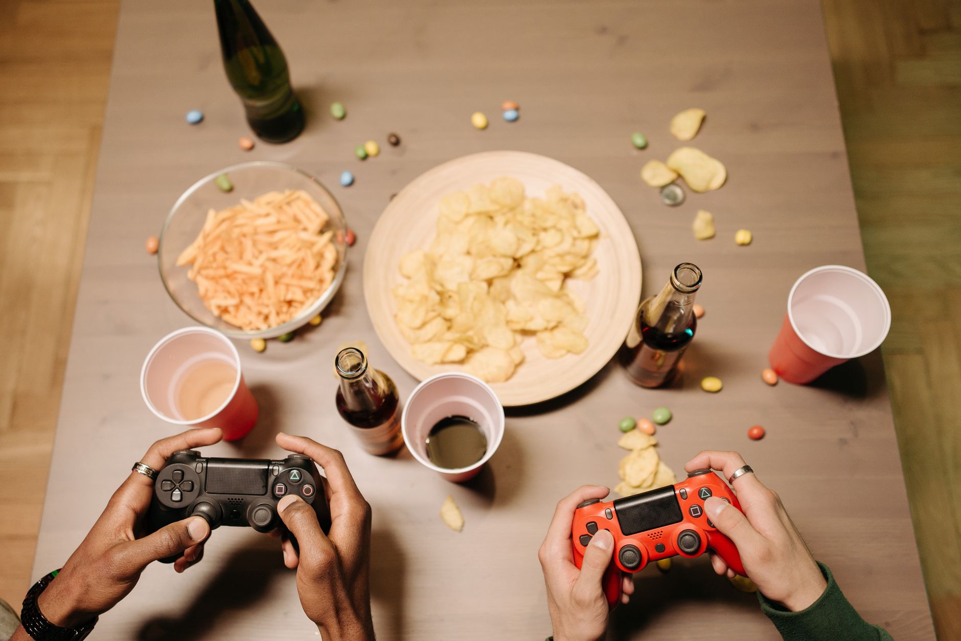 Two gamers playing video games with snacks and drinks on table, a perfect setup for gaming night. — How Casinos Build Long-Te