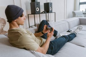 Casual young man playing mobile games on sofa with speakers in the background. — Reasons for selecting online casinos for act