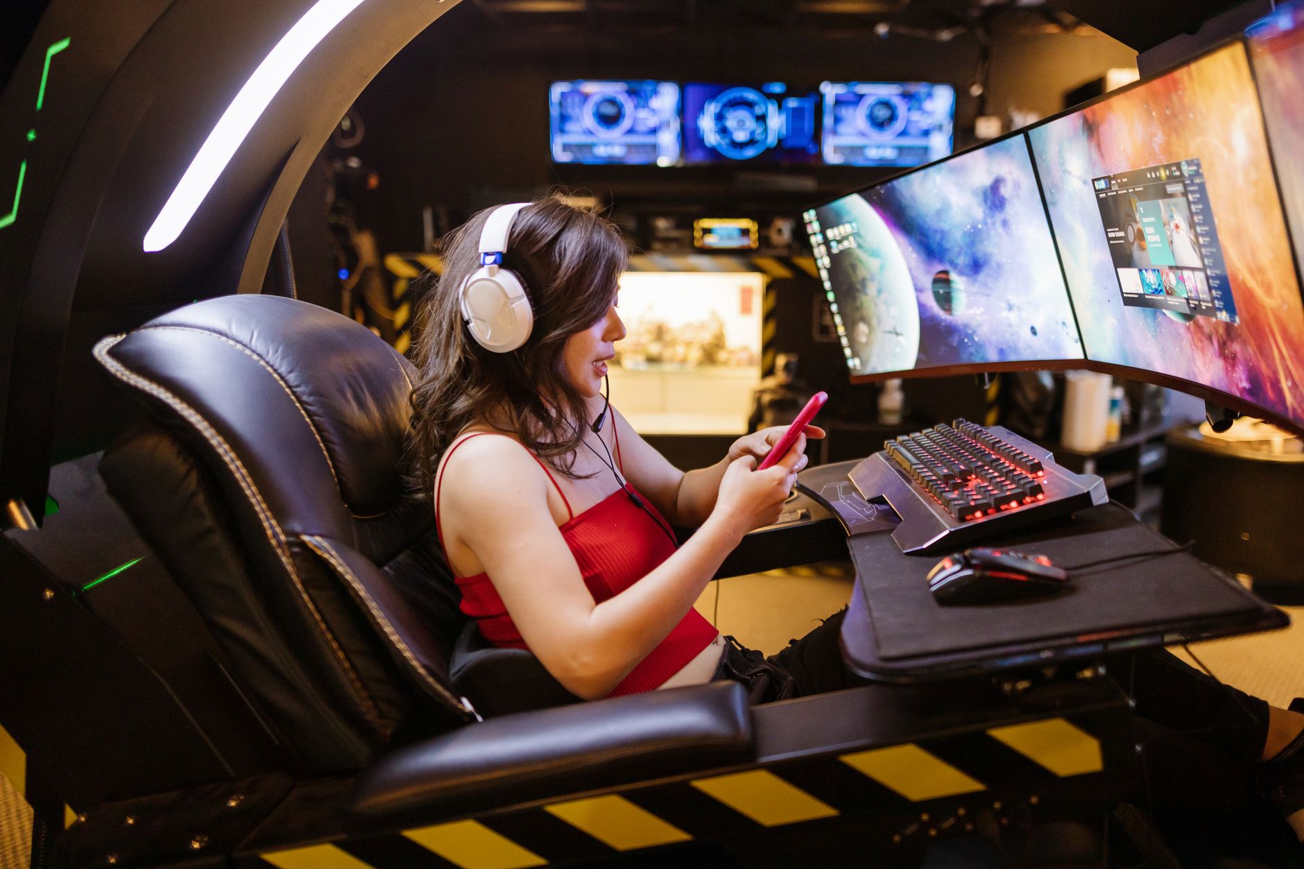 Young woman enjoying computer gaming at home with a high-tech gaming setup and smartphone. — Remaining in chargeinside acasin