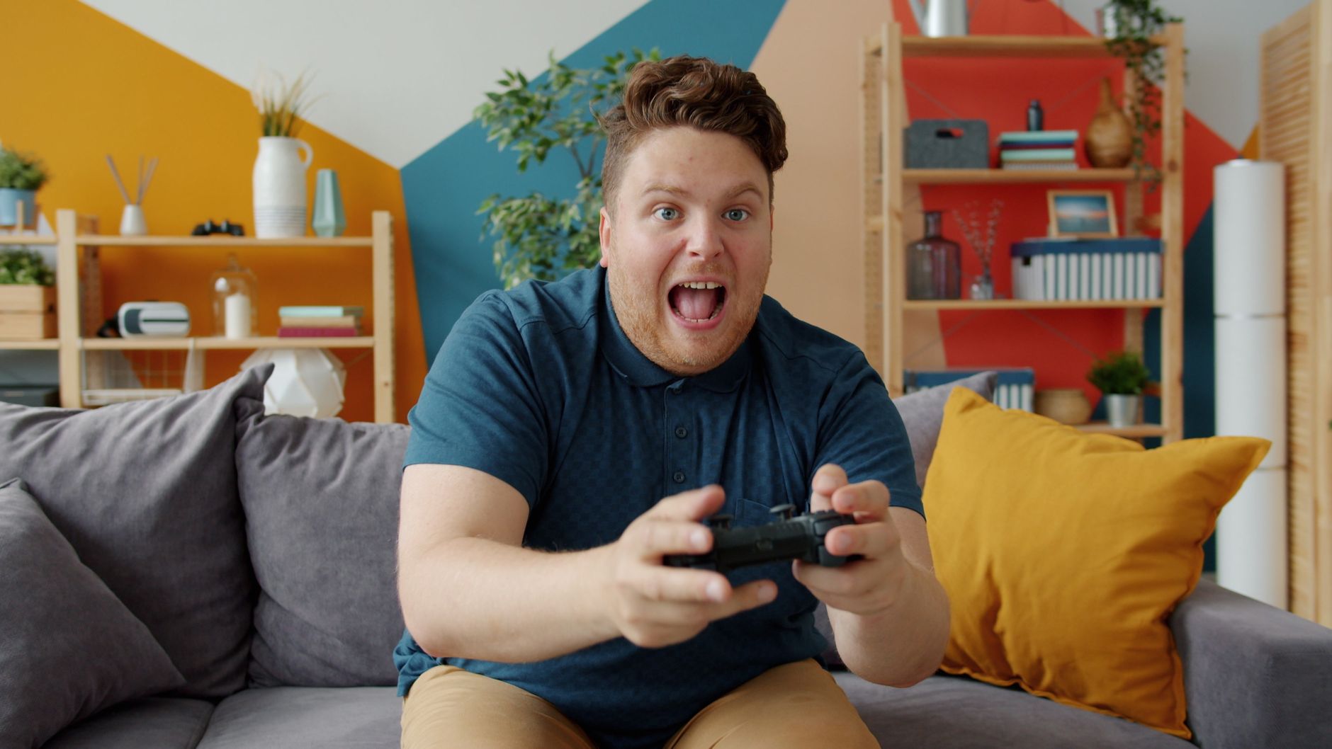 Enthusiastic adult male playing video game on console in colorful, modern living room. — Find Out What Makes Toto Sit