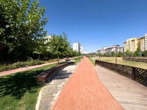 A vibrant, sunny park walkway with trees and buildings in Elâzığ, Türkiye. — Win Spectacular Prizes with the Thrillin
