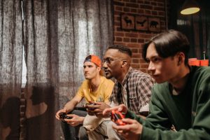 Three men focused on playing video games with controllers indoors. — The Ultimate Casino DestinationIs Joker123: Online Gamin